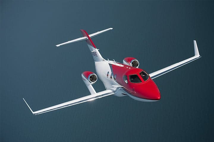 A HondaJet flying over the ocean.