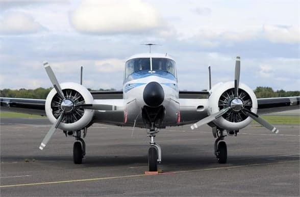 Beechcraft Model 18 with registration N8495A in flight, seen from below.