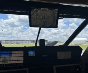 View from the cockpit showing the instrument panel and a screen displaying a map.