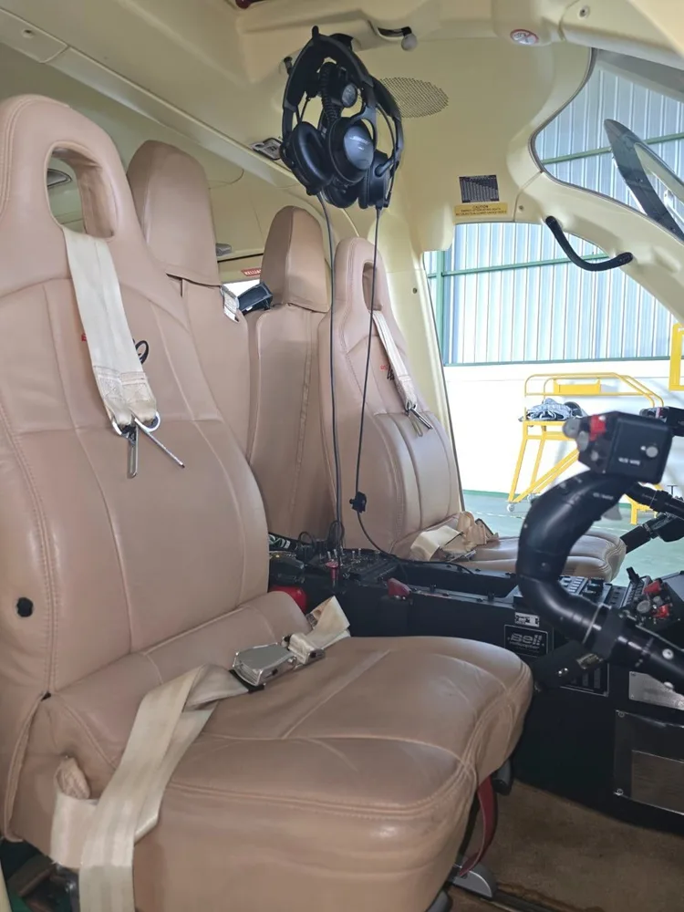 View of the helicopter cabin with tan leather seats and cockpit controls.