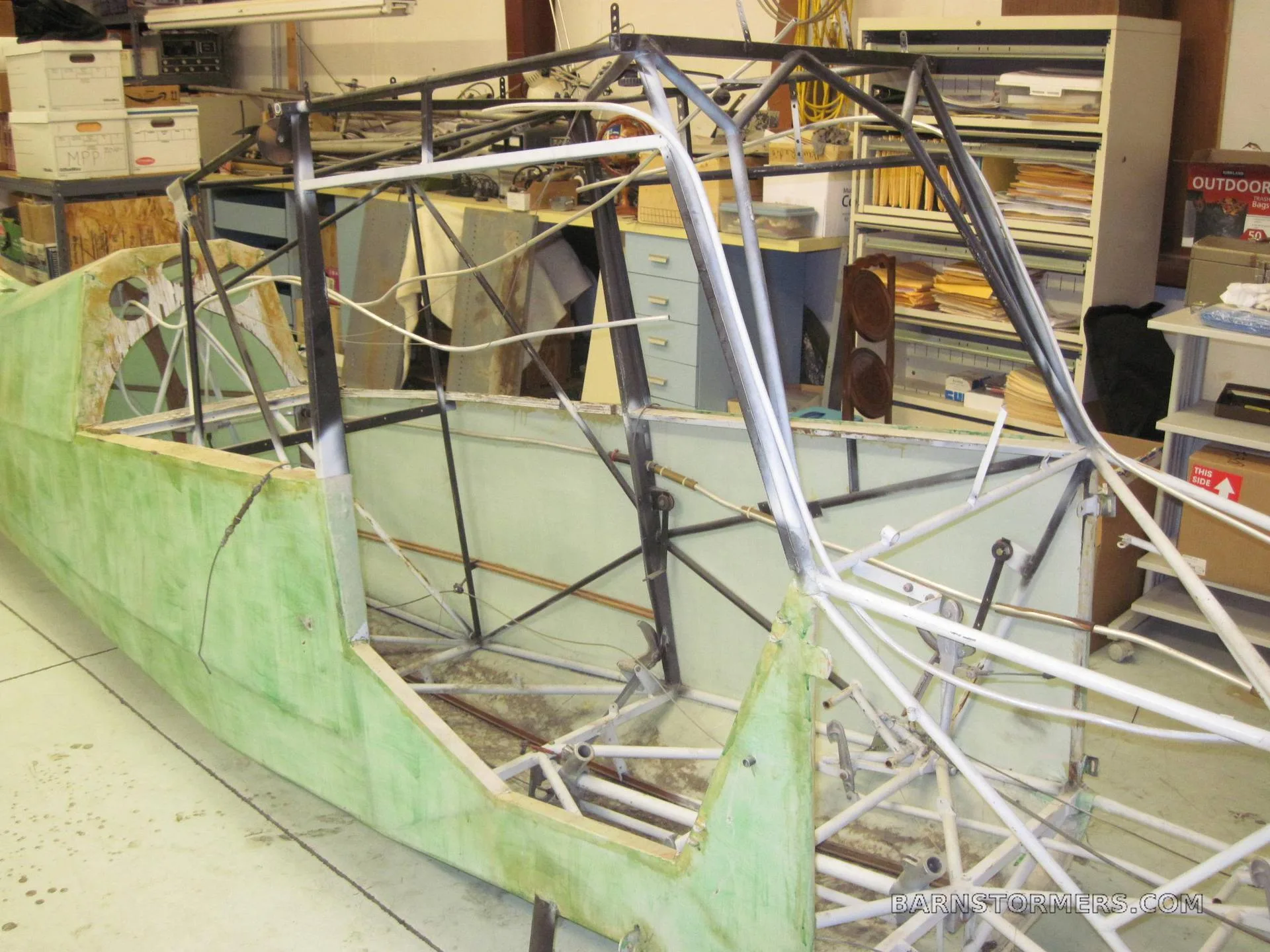 A close-up view of the metal frame and light green skin of an aircraft fuselage under construction.