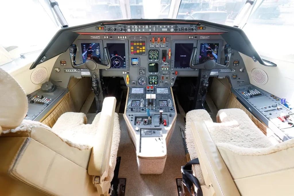 The aircraft cockpit features dual controls and multiple display screens.