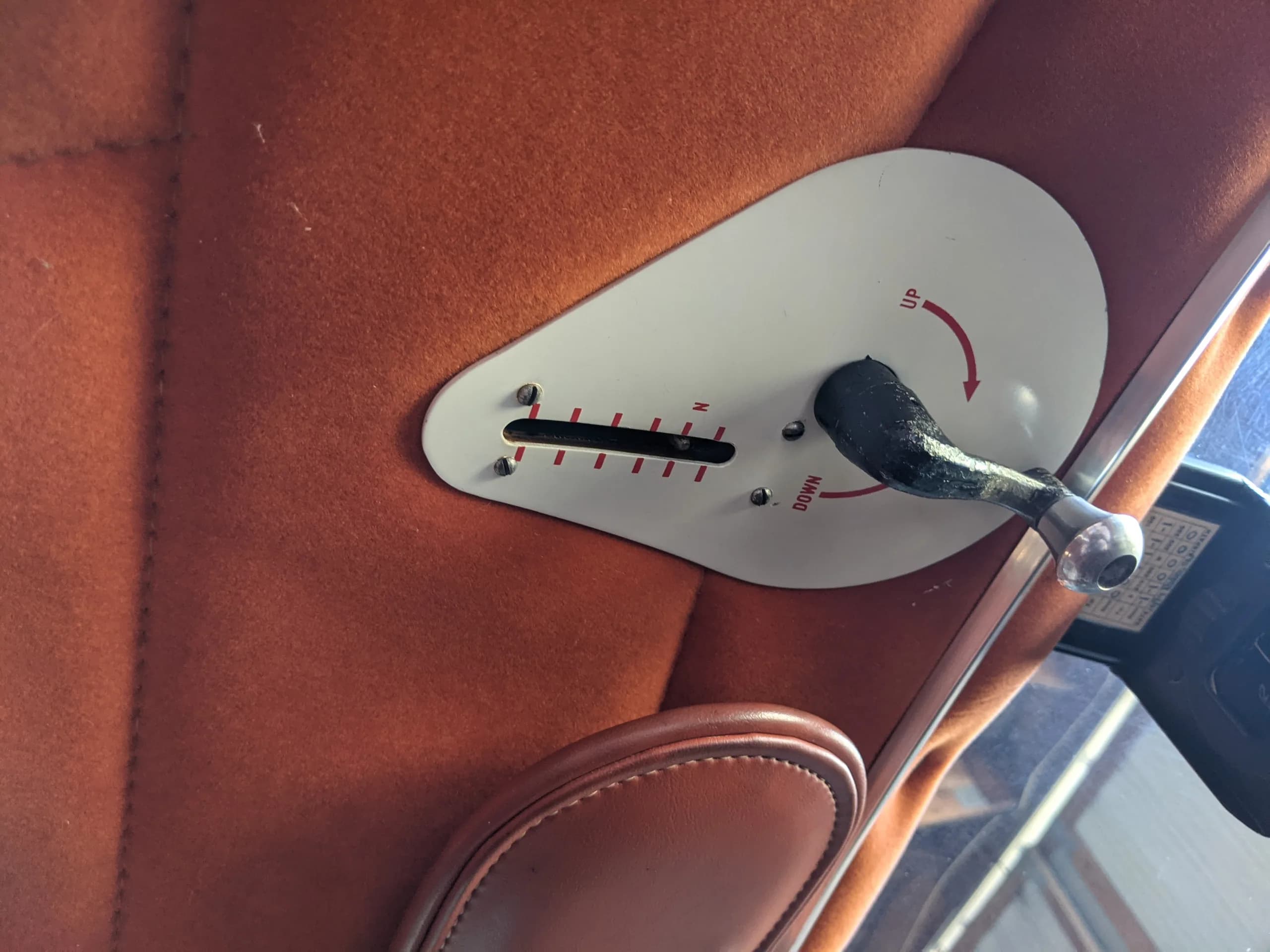 A close-up of a white control lever with "UP" and "DOWN" markings on the orange fabric interior panel.