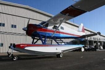 Front view of a float plane on a lake with mountains in the background.