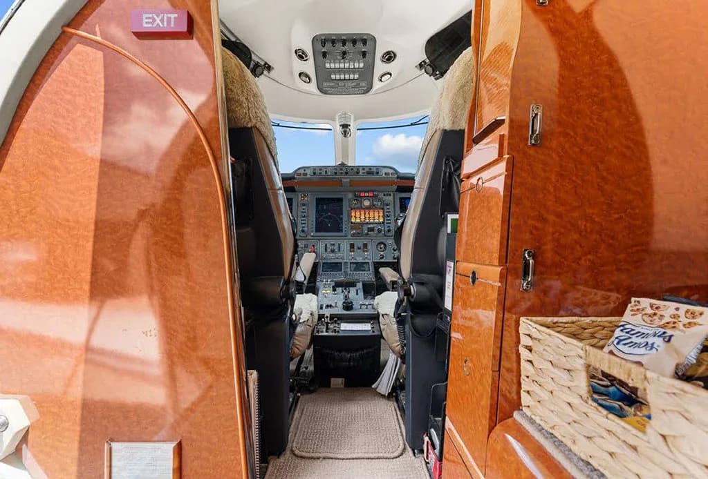 A view from the cabin looking directly into the cockpit of the private jet, showing the instrument panel and pilot seats.