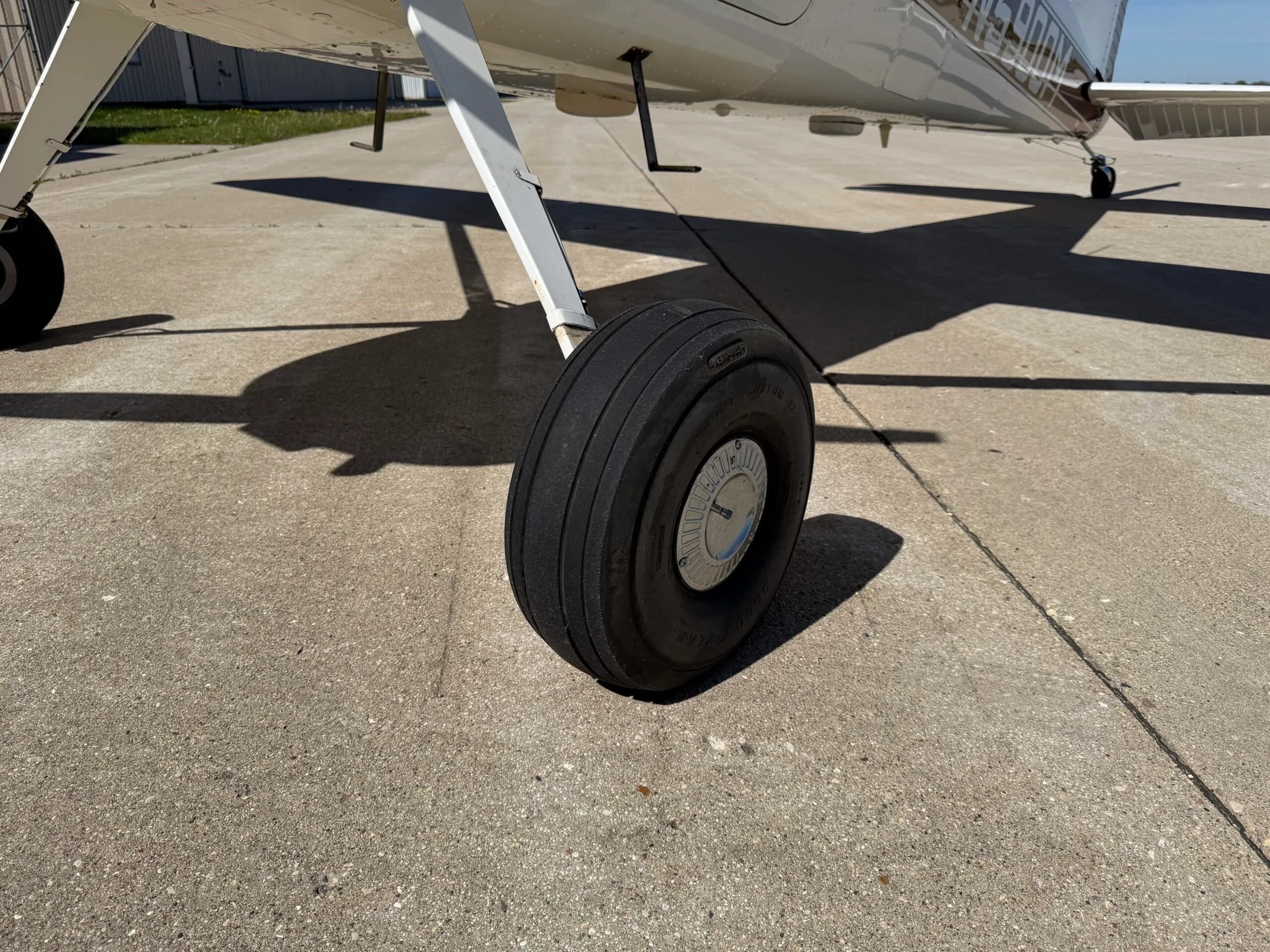 Close-up of the left main landing gear wheel of a Cessna 172 on concrete.
