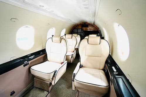 The interior of the aircraft features cream-colored leather seats and oval windows.