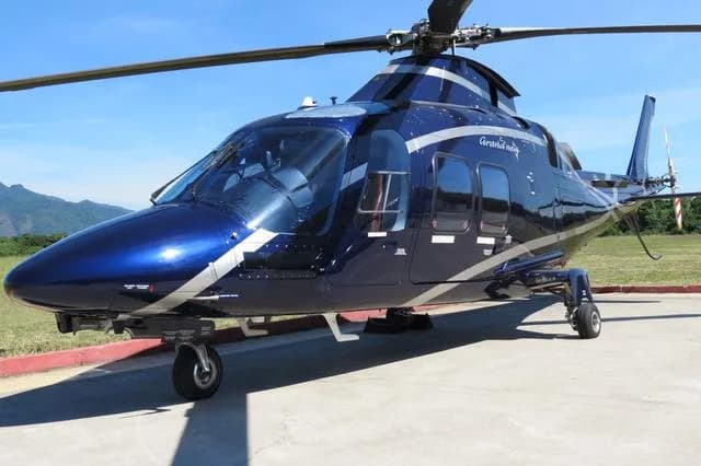 A blue and silver AgustaWestland AW109 GrandNew helicopter on the ground.