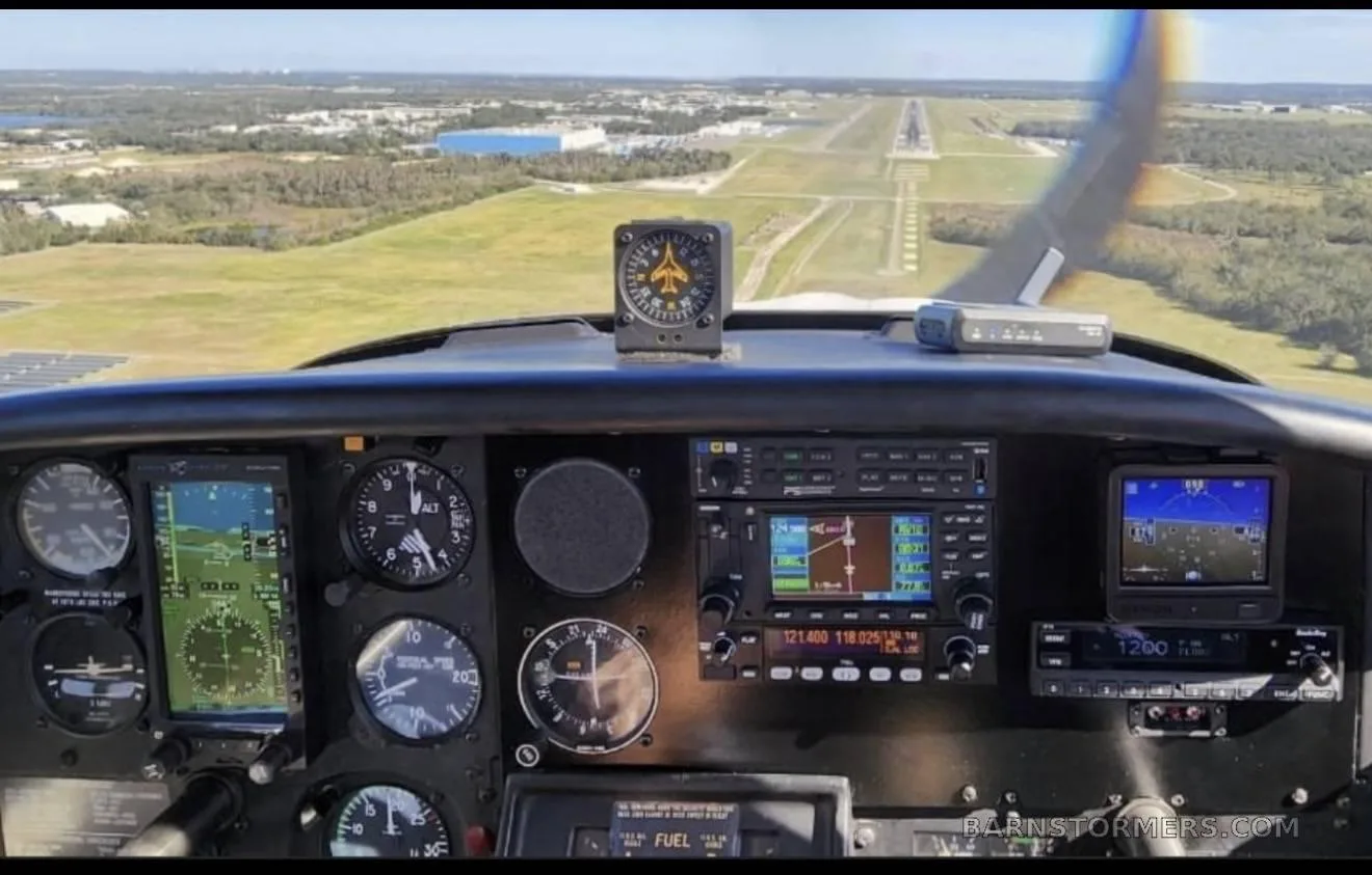 View from a cockpit showing the instrument panel with a runway visible through the windshield.