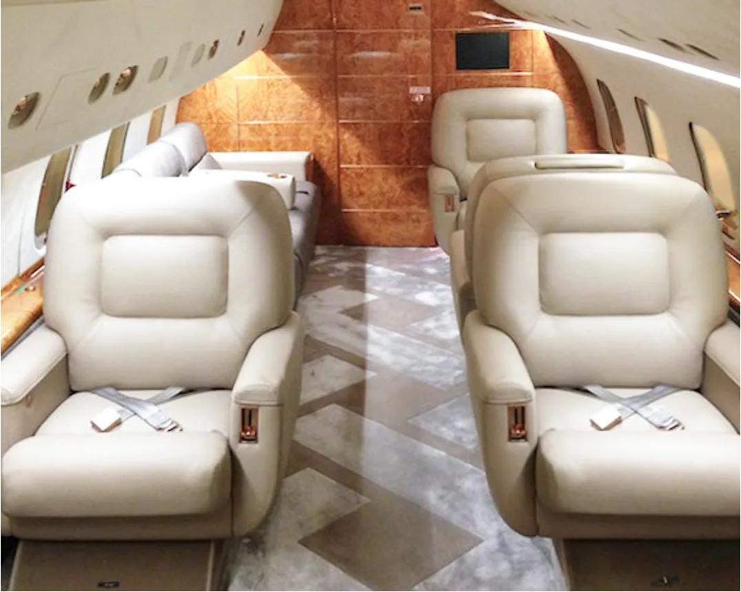 Aircraft interior with tan leather seats and wood paneling.