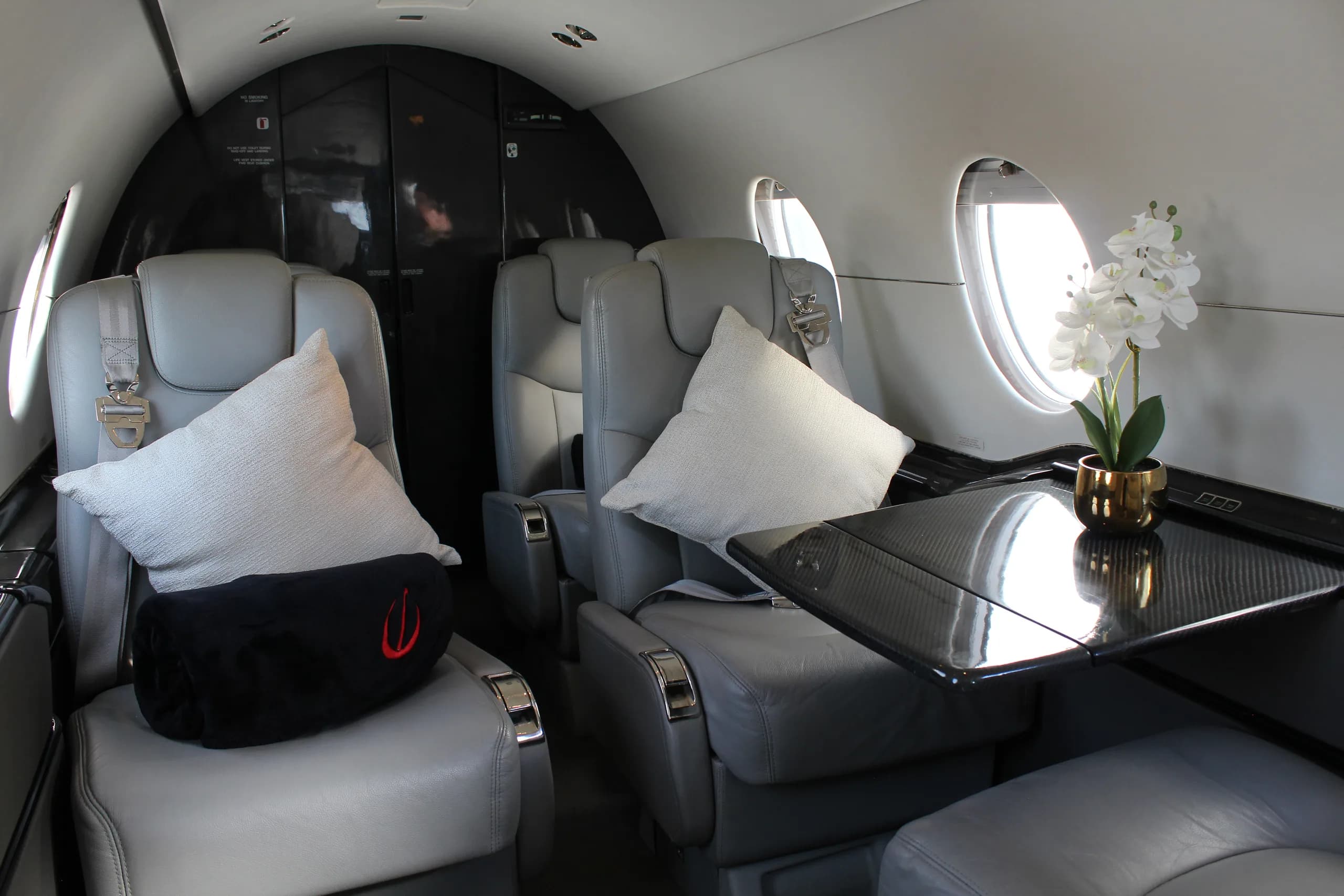 Interior view of the aircraft cabin with gray leather seats and a small table.