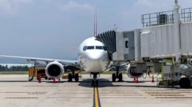 A passenger jet connected to a jet bridge at an airport gate.