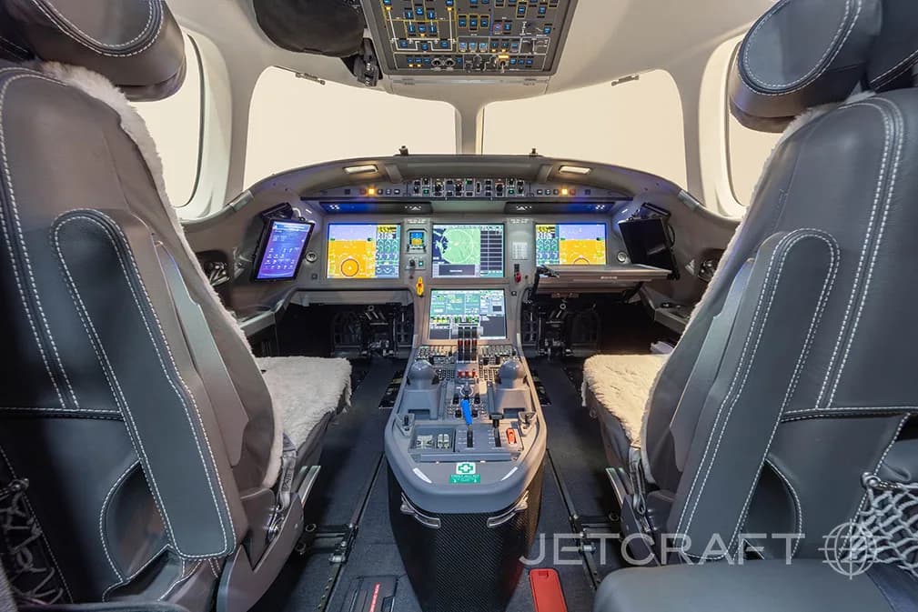 The modern cockpit of a business jet, featuring multiple digital displays and a central control pedestal.