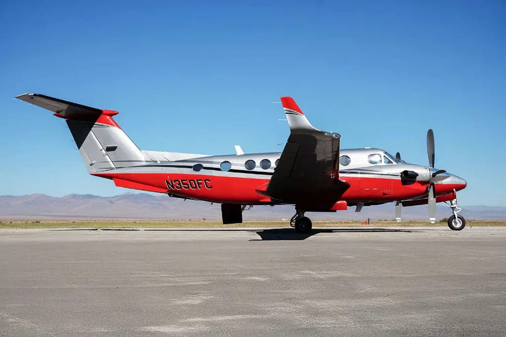 Side view of a red and silver Beechcraft King Air N350FC parked on an airfield.