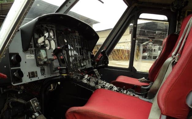 The cockpit of a Bell 212 helicopter with red seats.