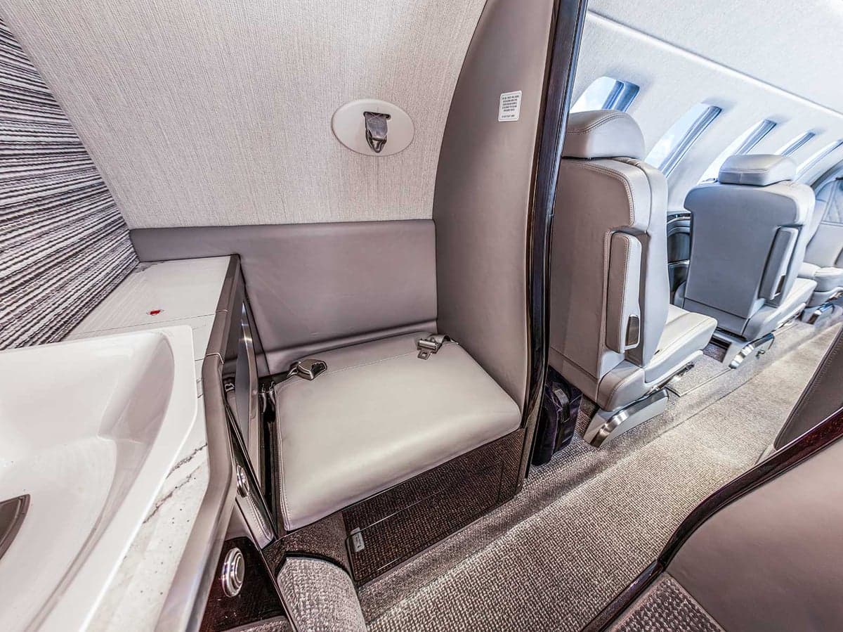 View of the Citation CJ4 cabin featuring a side-facing seat and gray leather seats.