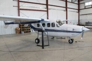 Side view of a white and blue aircraft inside a hangar.