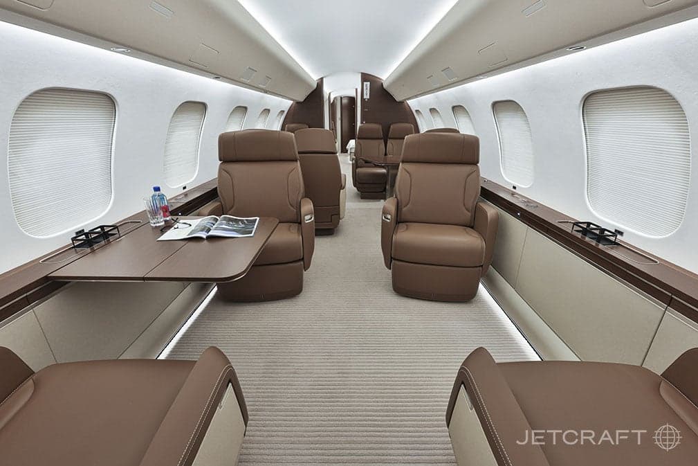 Aircraft cabin with brown leather seats and tables.