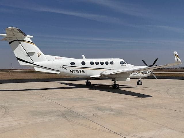 A King Air 350 with a white and gold paint scheme is parked on the tarmac.