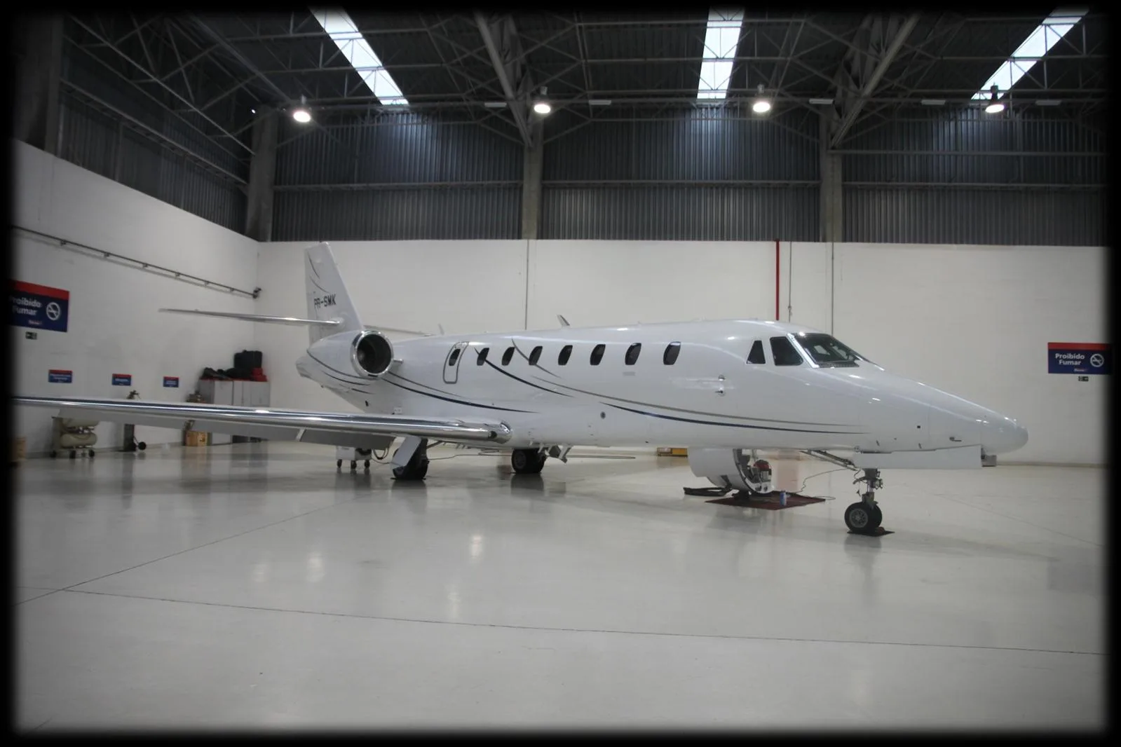 A white jet aircraft parked inside a hangar.