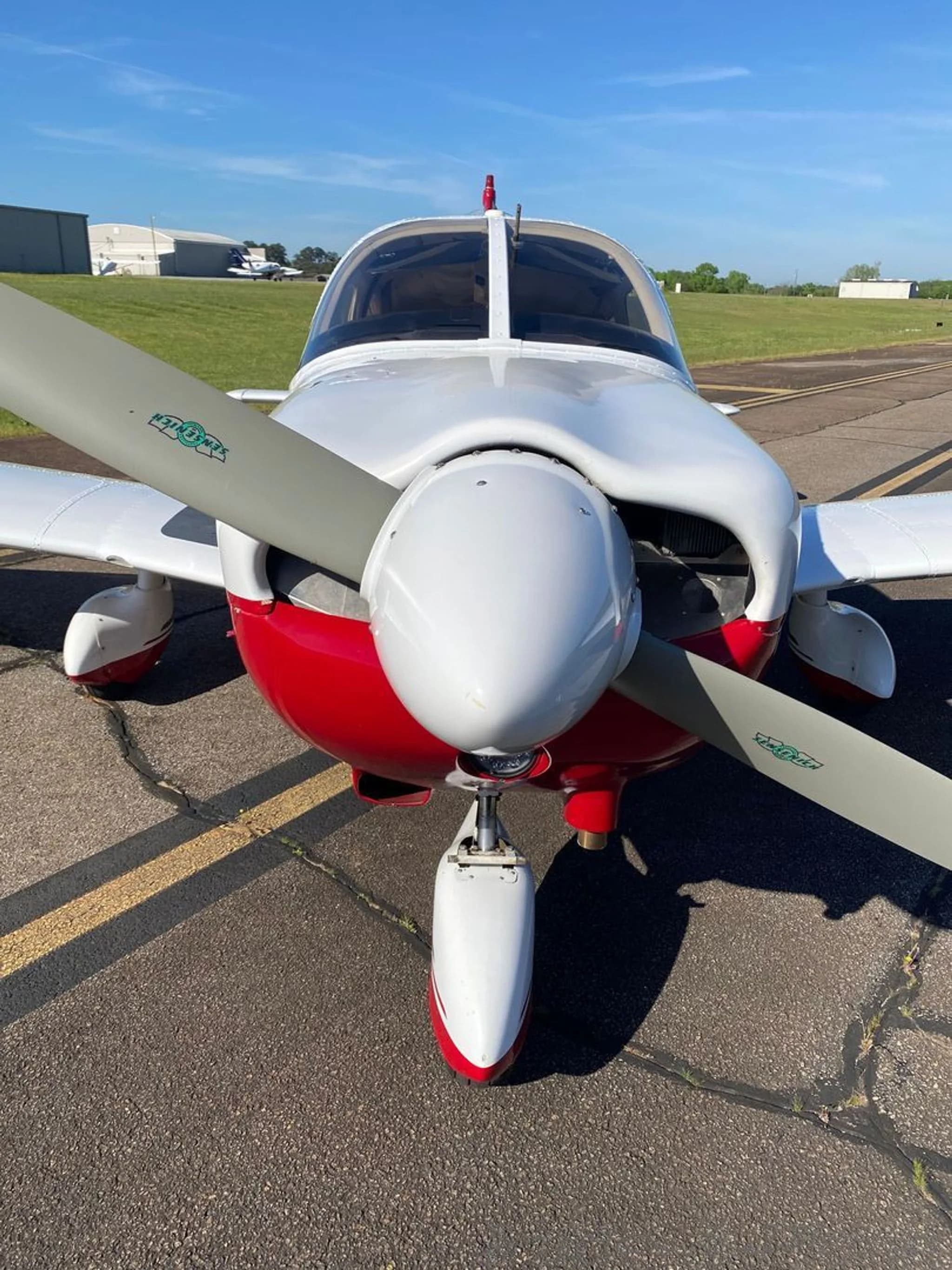 A front view of the white and red Piper Arrow II (N926CK) showing the propeller and nose gear on the tarmac.