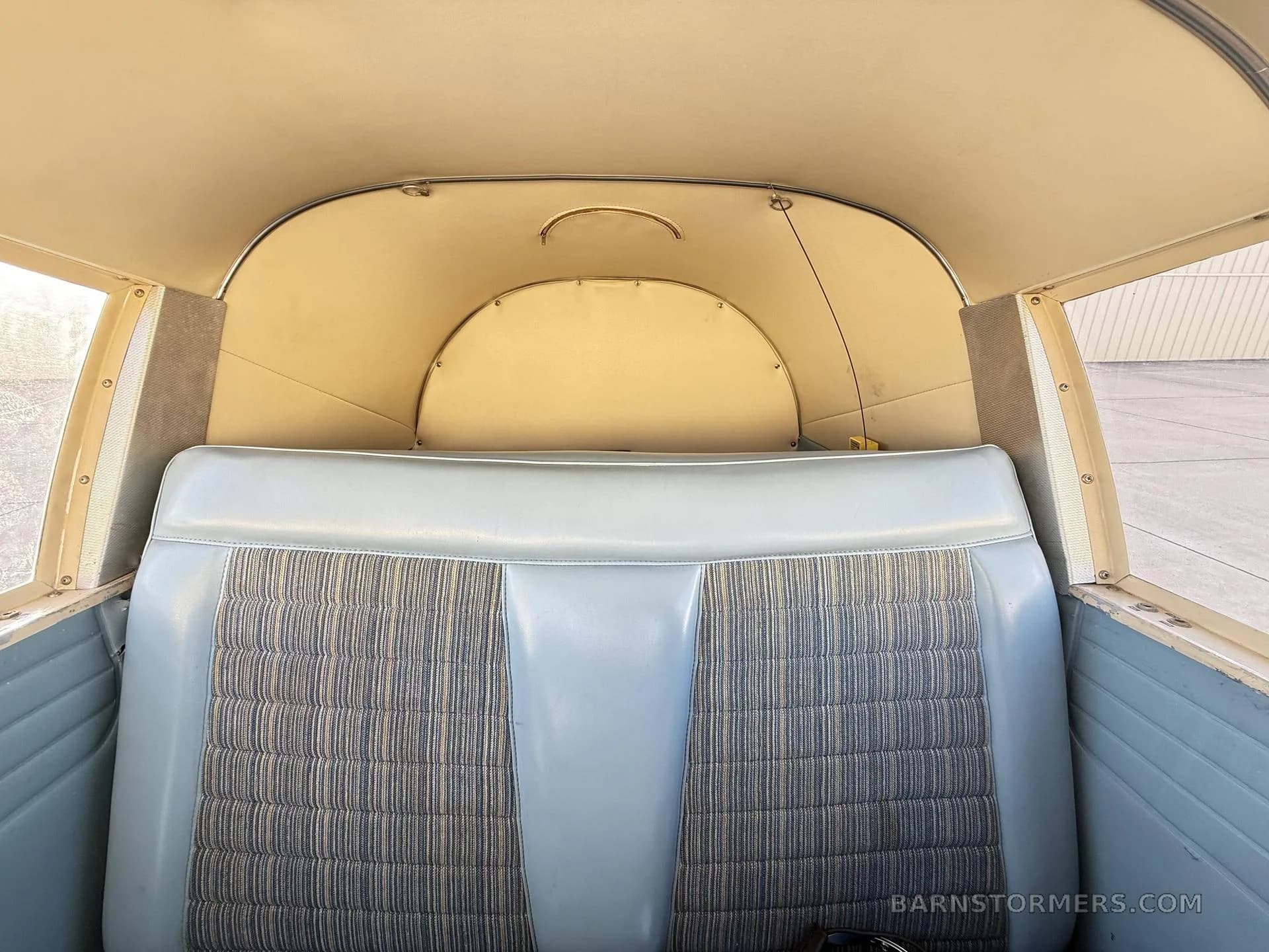 The light blue and striped rear passenger seats of a small aircraft cabin.