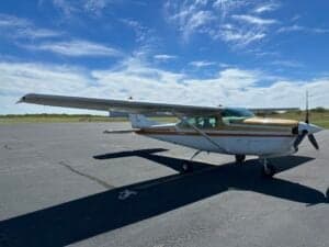 A Cessna 182RG on the tarmac with a white and gold paint scheme.