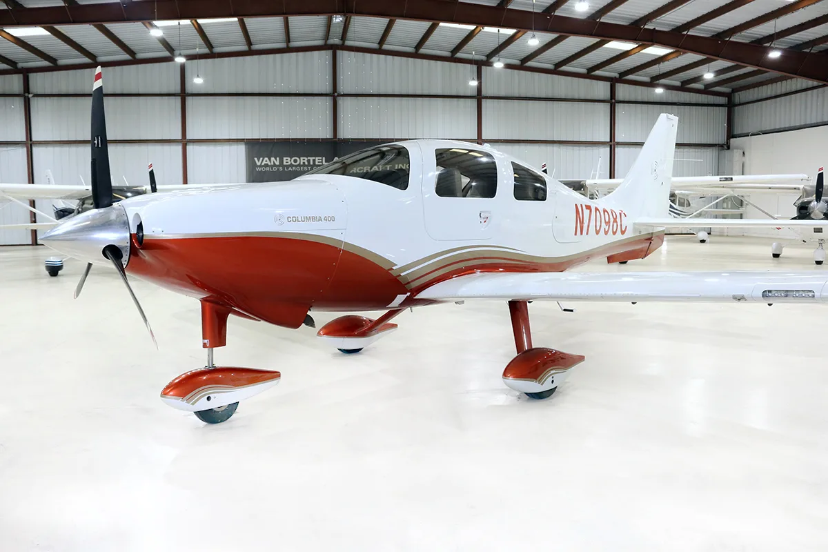 A white and red Columbia 400 aircraft with registration N7098C parked in a hangar.