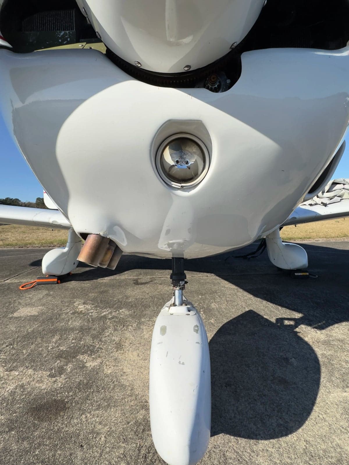 Close-up of the nose gear and propeller hub of a Piper Cherokee aircraft.