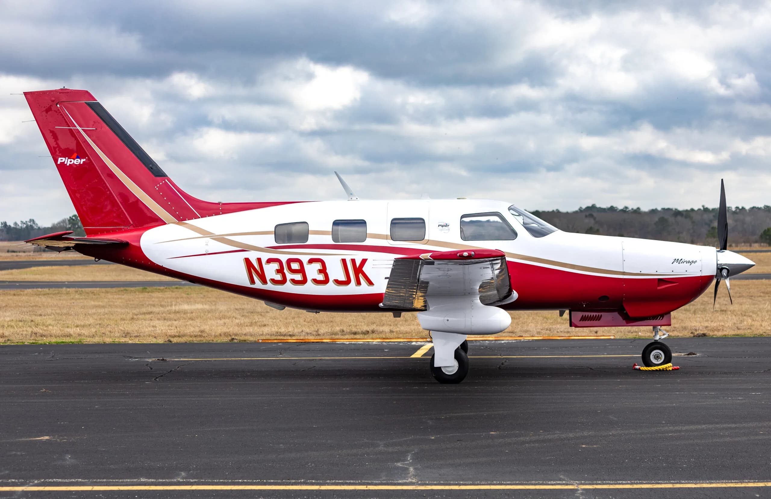 Side profile of the Piper Mirage N393JK with its distinctive red and white livery.