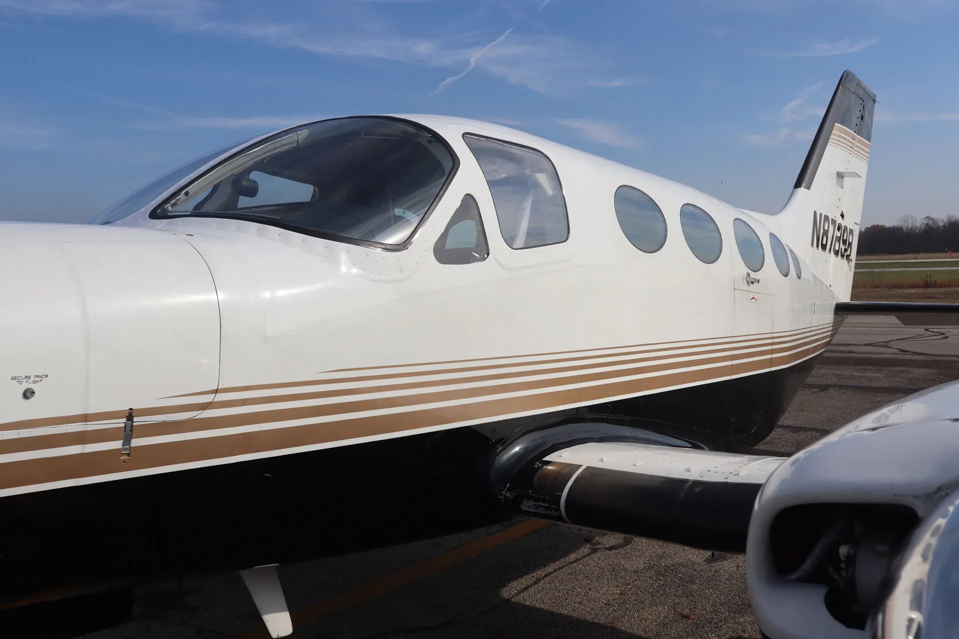 A close-up of the N8789B aircraft shows the fuselage and windows with a black and gold paint scheme.
