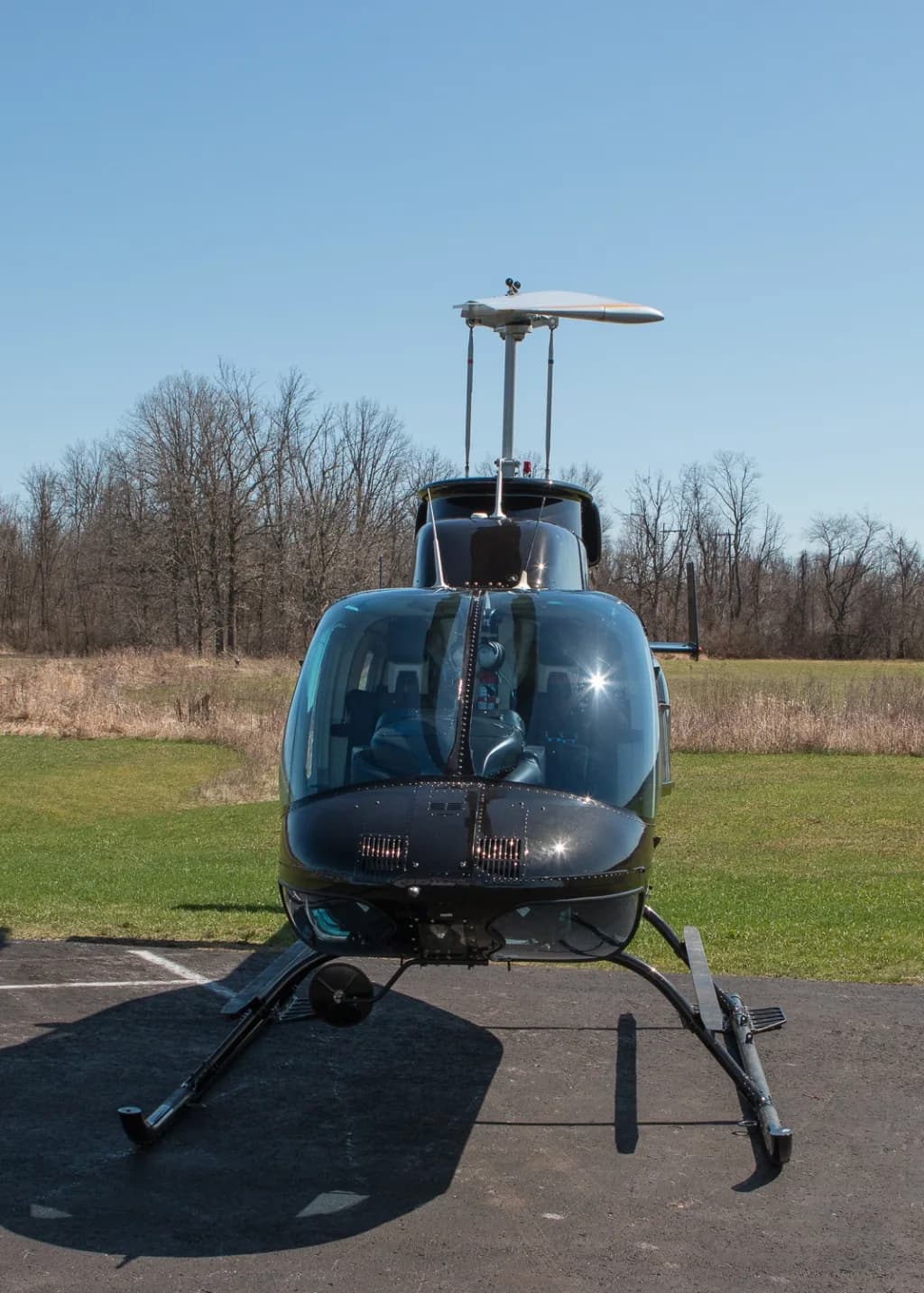 A head-on view of a black Bell 206 helicopter with registration C-GVHD on a tarmac.