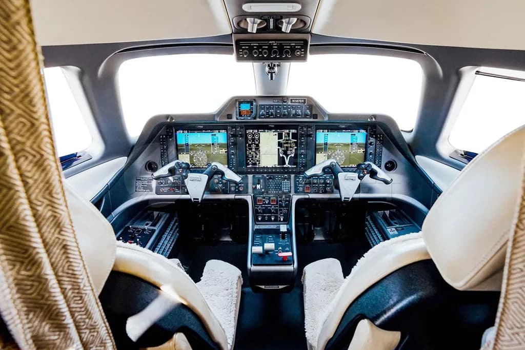 The cockpit of an Embraer Phenom 300, showing the instrument panel with multiple displays and controls.
