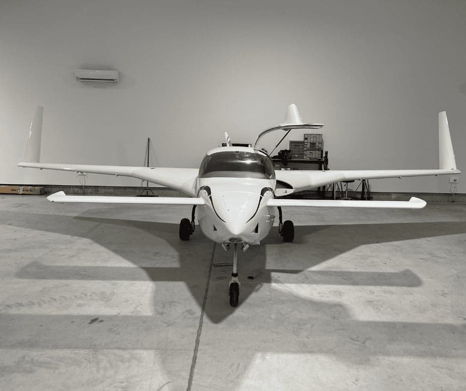 A white aircraft parked inside a hangar.