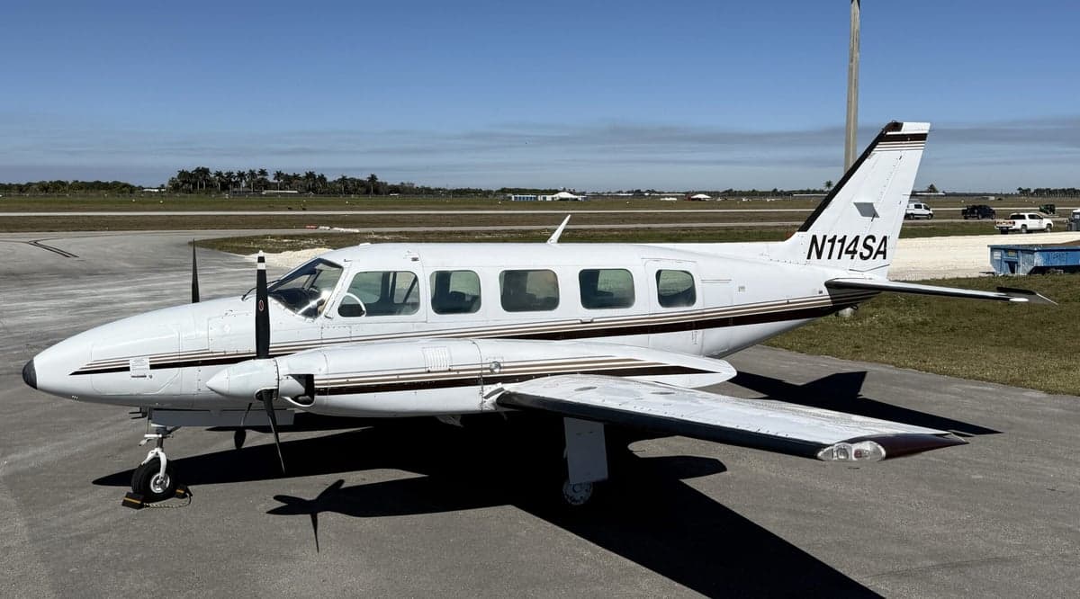 Side view of the twin-engine aircraft N114SA on the tarmac.