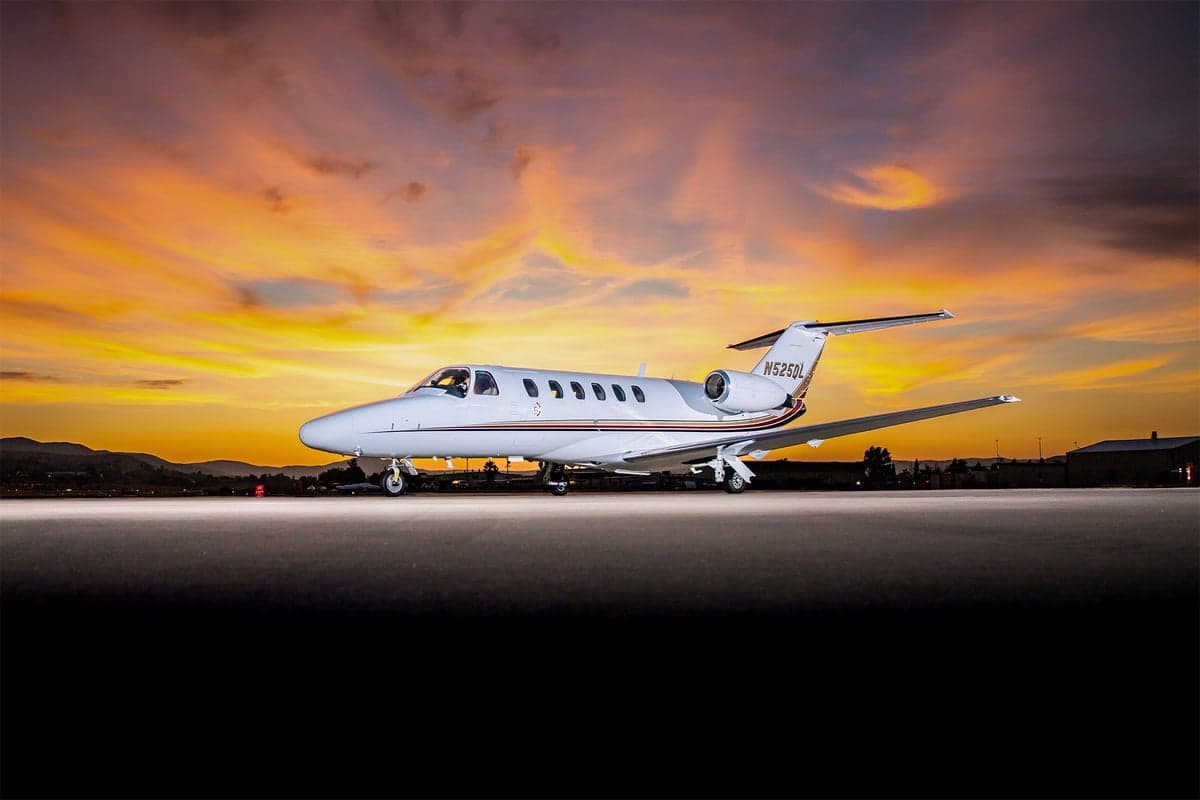 A Cessna Citation CJ2 sits on the tarmac at sunset.