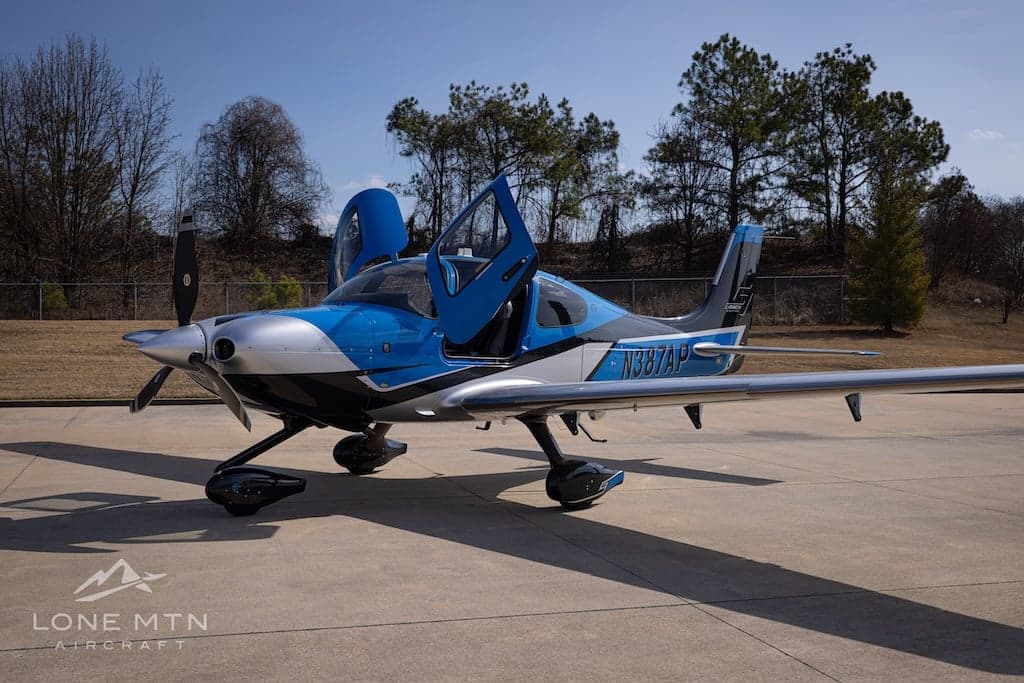 Cirrus SR22T with blue and silver paint scheme on the ramp with doors open.