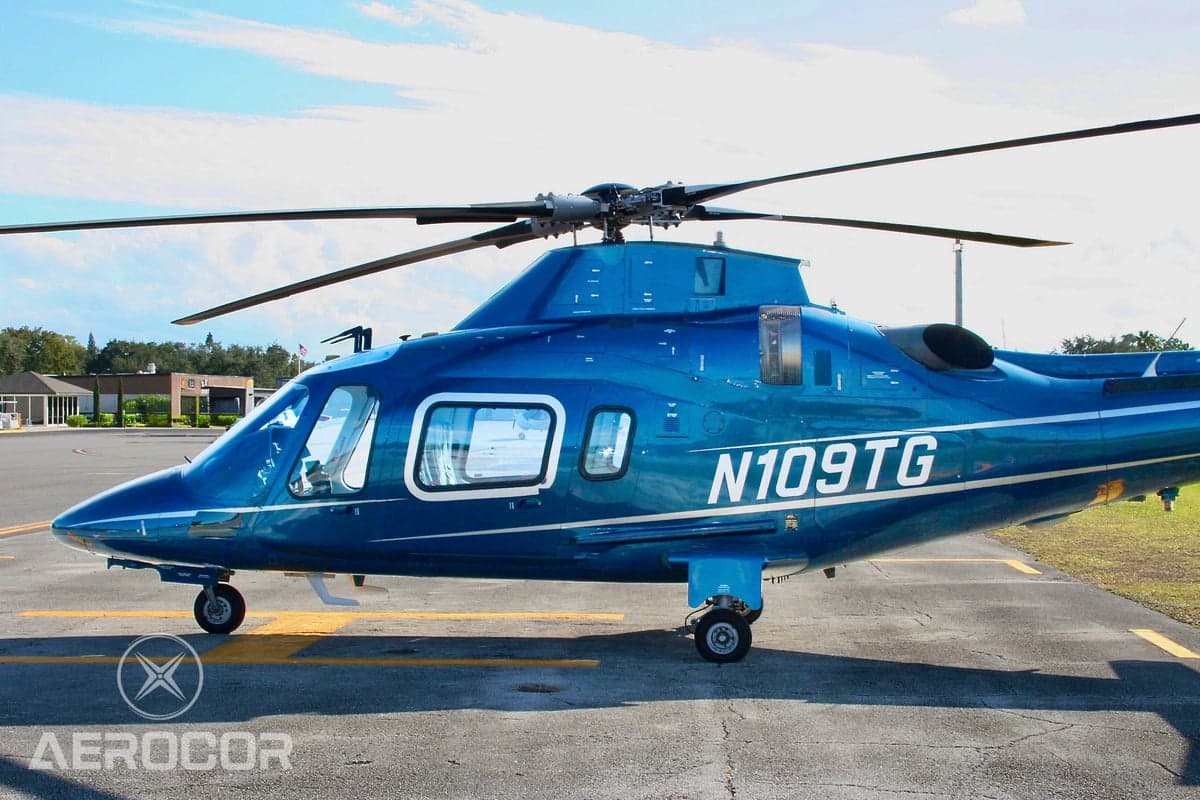 Close-up side view of the cockpit and cabin of a blue AgustaWestland AW109 helicopter (N109TG).