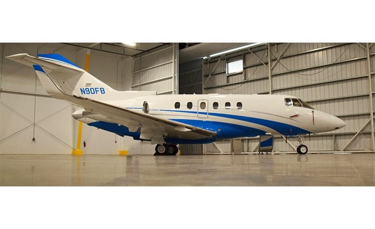 A Hawker jet with blue and white paint scheme is parked inside a hangar.