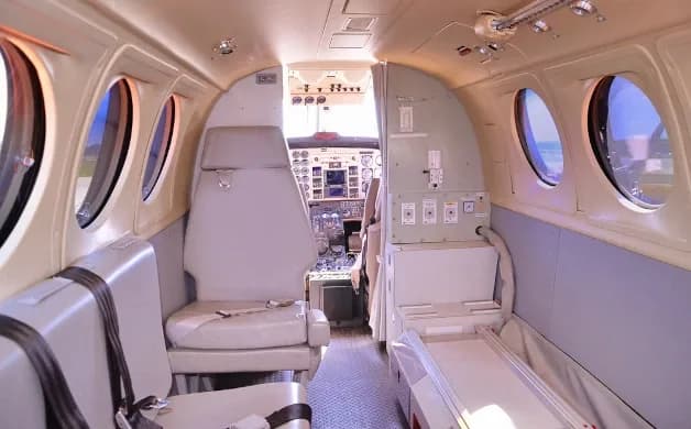 The interior cabin of an aircraft, configured for medical transport, looking towards the cockpit.