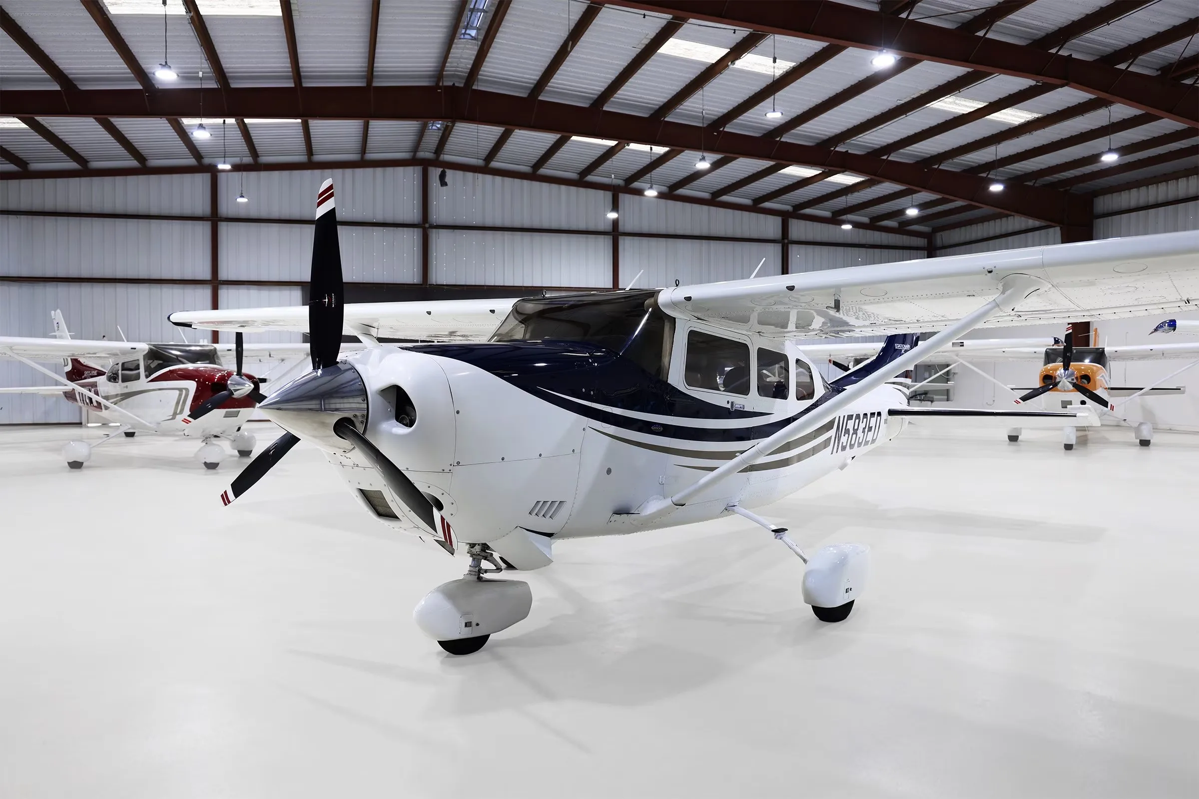 A front-quarter view of a white and blue Cessna 206 Stationair TC aircraft with tail number N583ED in a hangar.