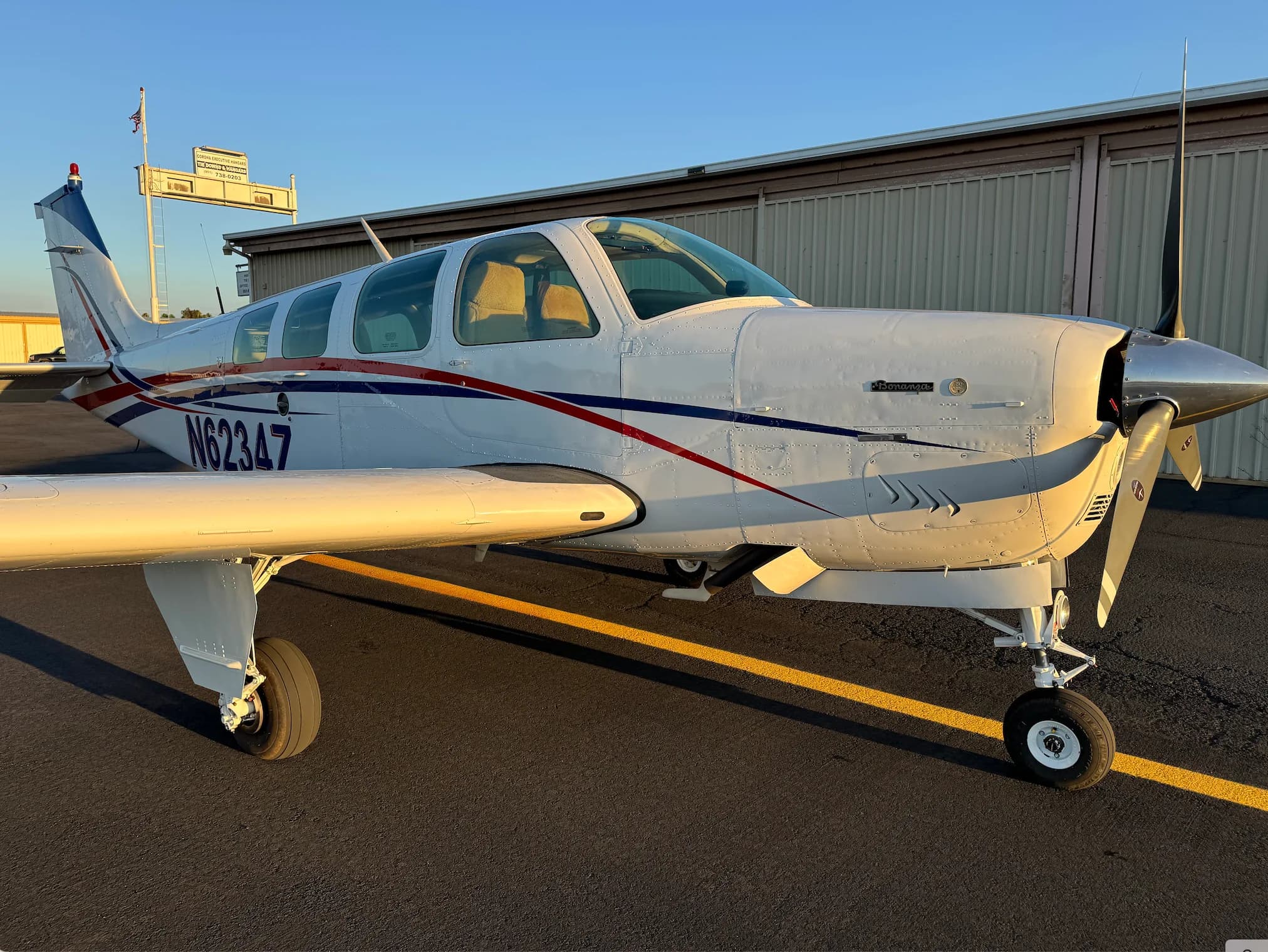 Close-up of the nose of a white and red Beechcraft Bonanza N6234Z on the tarmac.