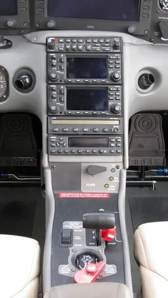 The center console and lower instrument panel of a Cirrus cockpit, showing radio stacks, throttle, and flap controls.