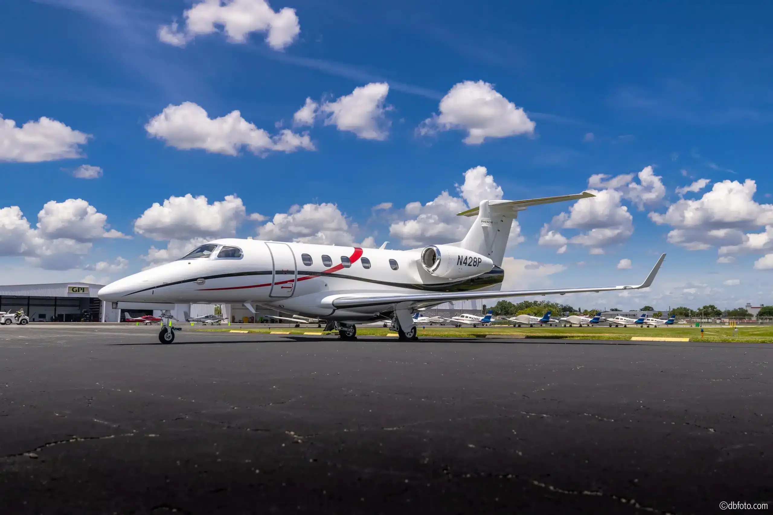 Side view of a Phenom 300 aircraft with registration N428P on the tarmac.