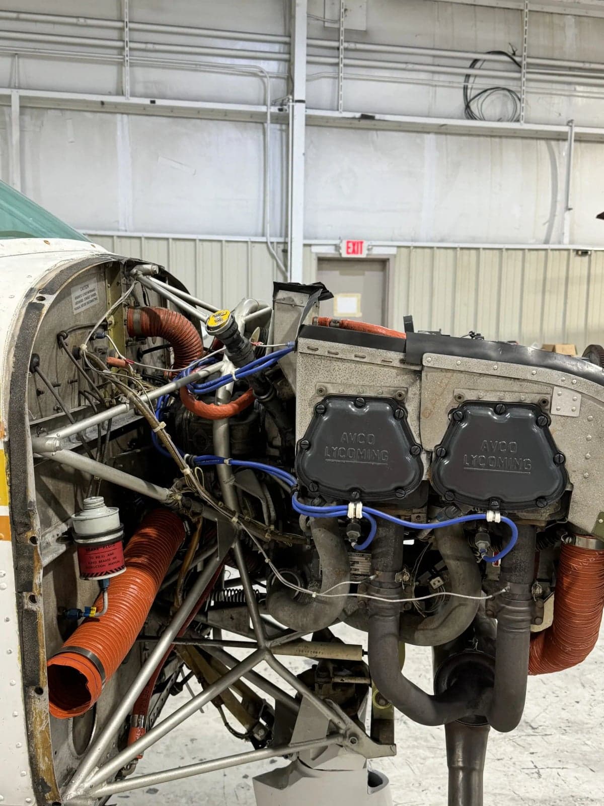 A Lycoming aircraft engine with its cowling removed, showing internal components in a hangar.