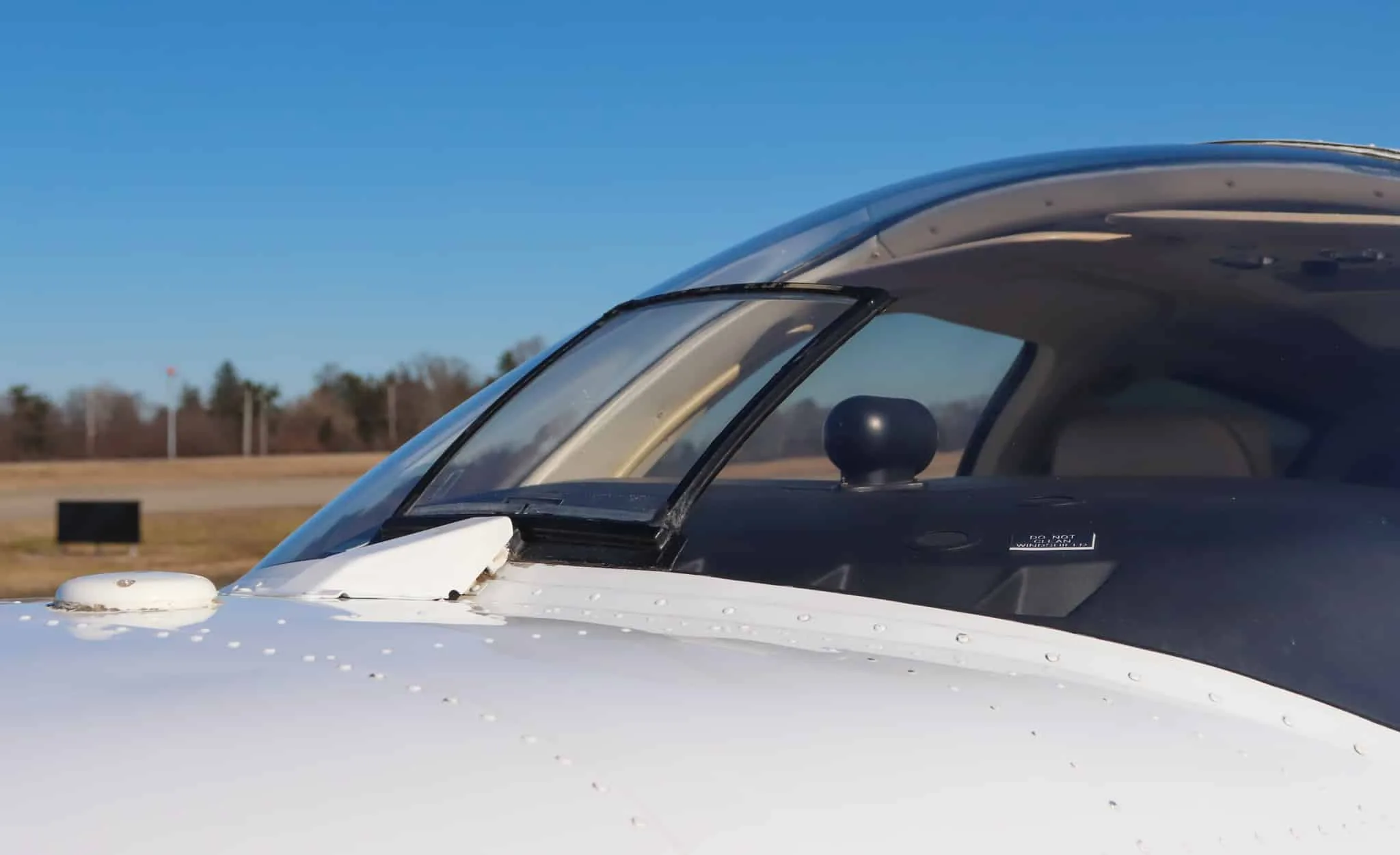 Close-up view of the cockpit windshield and nose of a white Beechcraft Baron N204G.