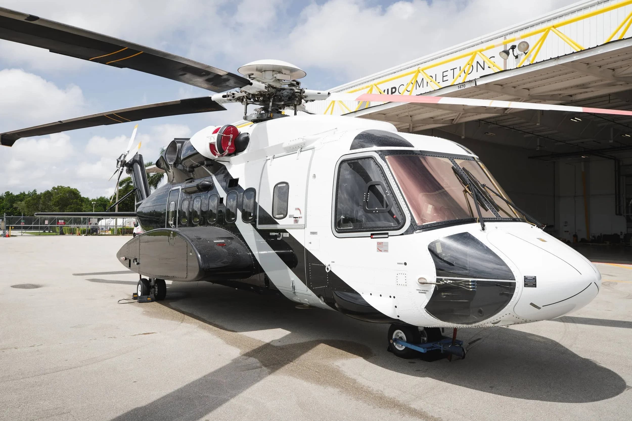 A black and white helicopter is parked in front of a hangar.