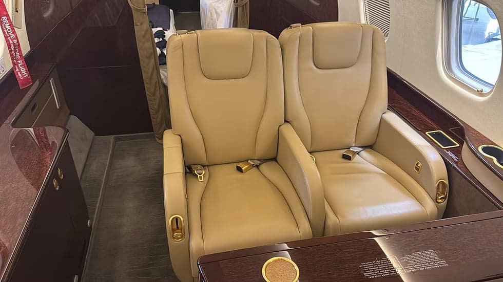 Interior view of the aircraft's cabin with leather seats and fold-out tables.