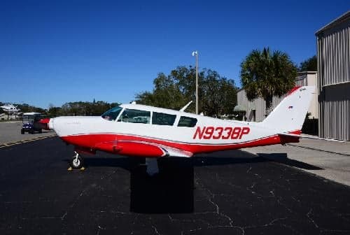 A white and red painted aircraft, N9338P, is parked on the tarmac.