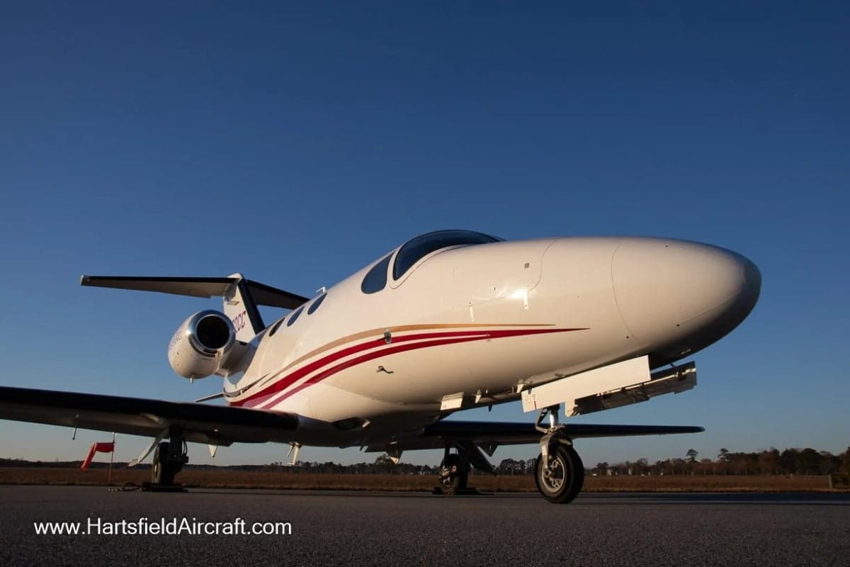 A Cessna Citation Mustang with a white and red paint scheme is parked on the tarmac.